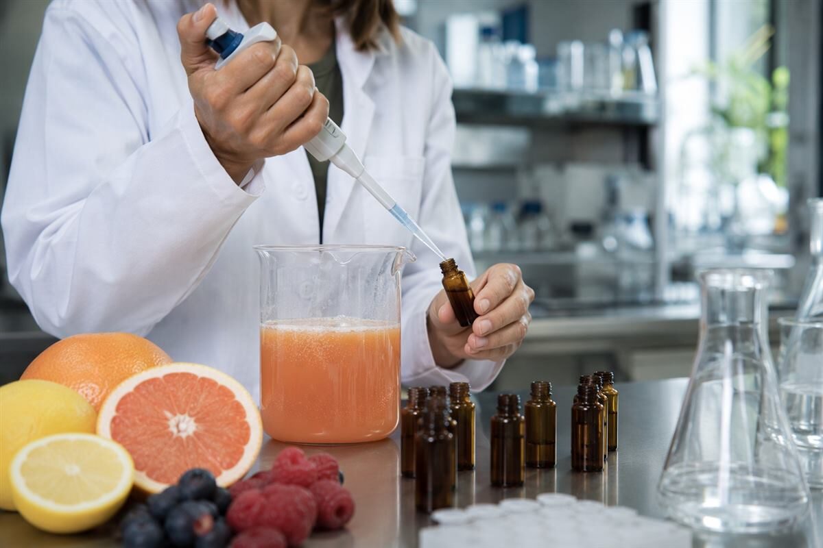 A food flavor scientist measures fruit-punch prototypes, illustrating a controlled beverage flavor-development workflow.